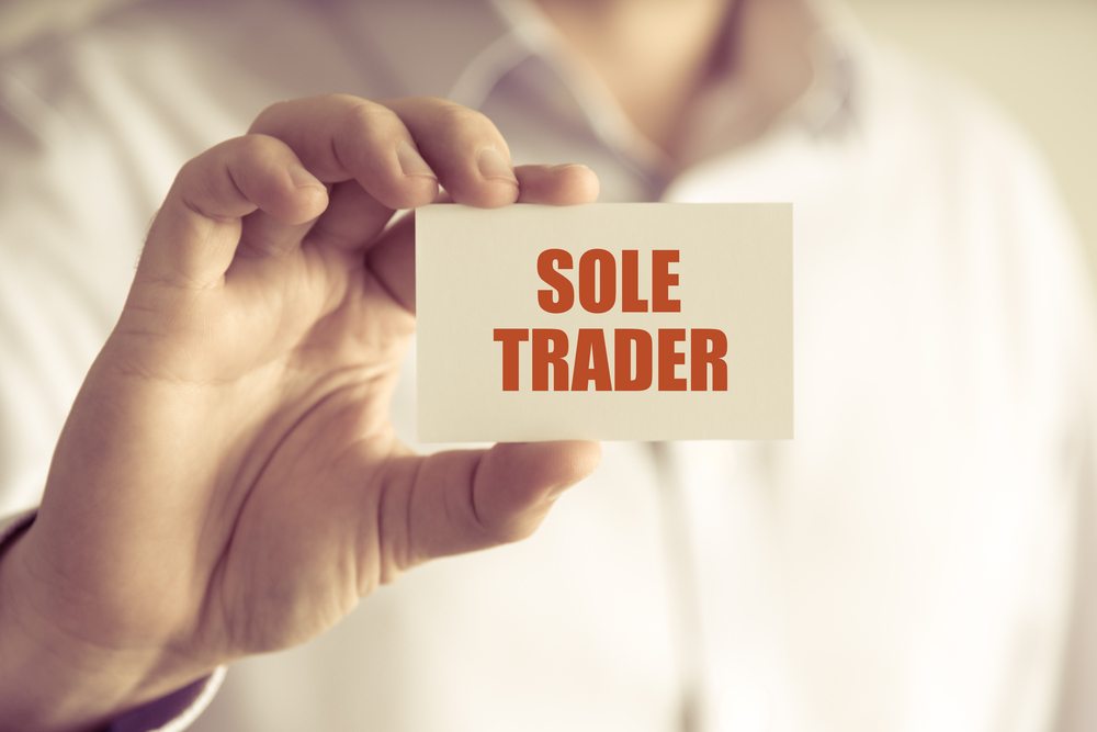 businessman holding a card with text SOLE TRADER,